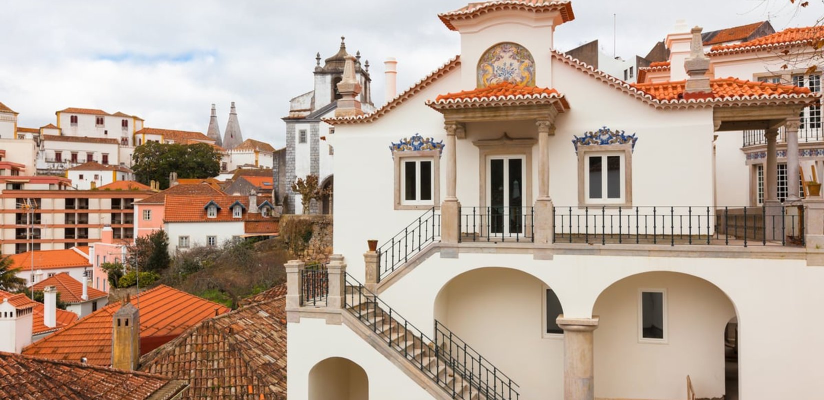 A white villa with painted azulejo panels above the rooftops of Sintra